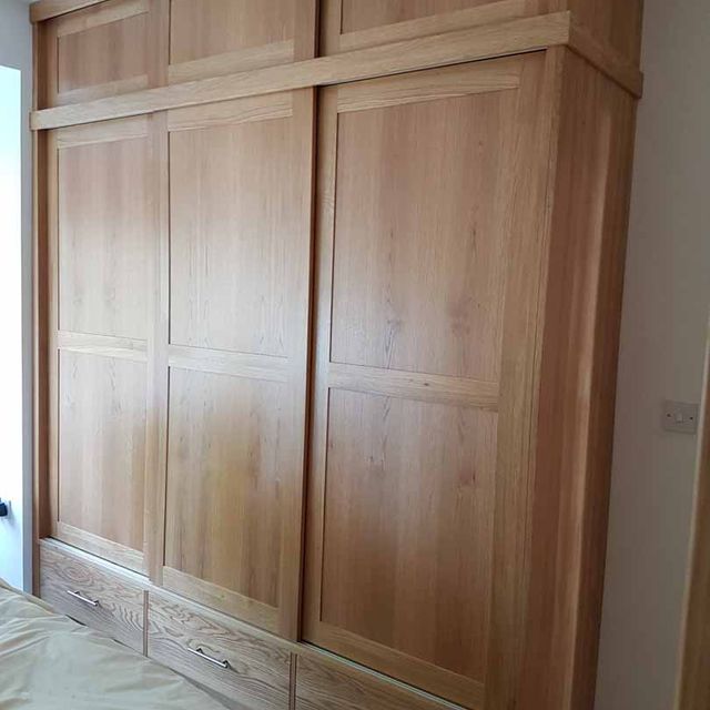 A built in oak wardrobe featuring sliding doors